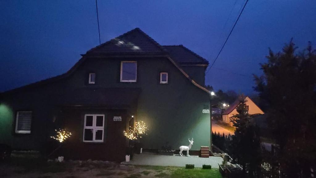 a house with a deer standing outside of it at night at Dom nad Jeziorami in Łubowo