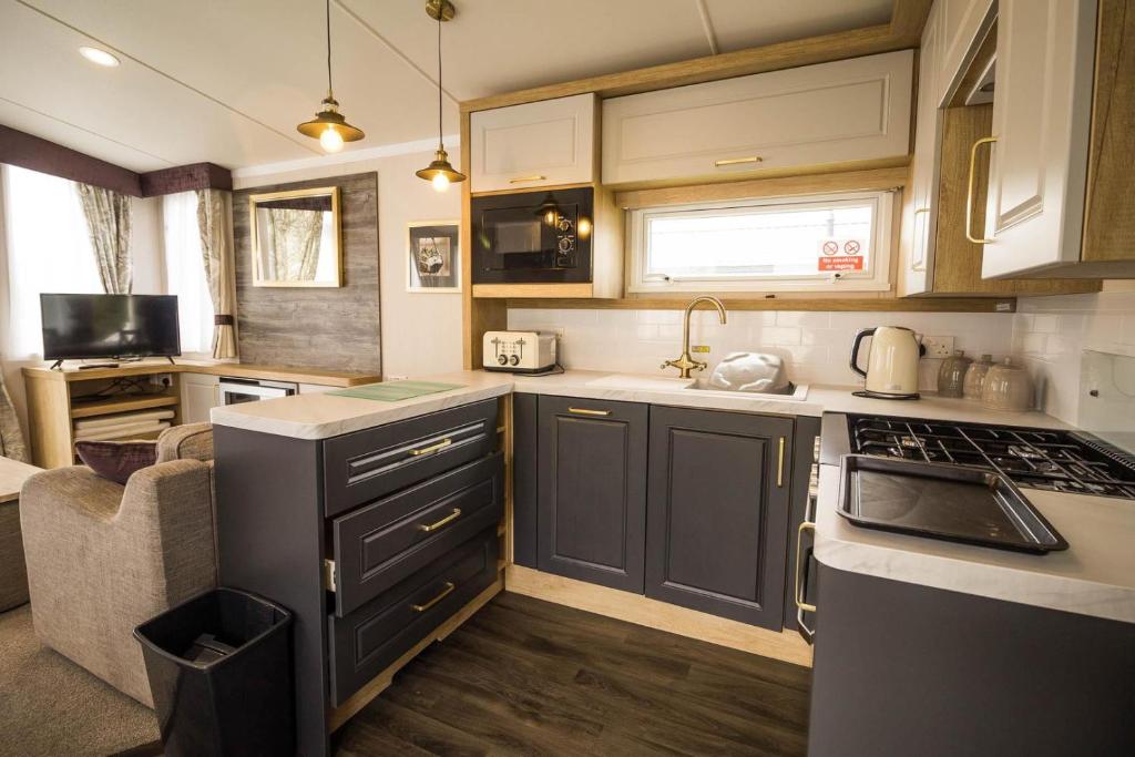 a kitchen with a sink and a stove top oven at Modern Caravan At Caldecott Hall With Decking In Norfolk, Sleeps 8 Ref 91068c in Great Yarmouth