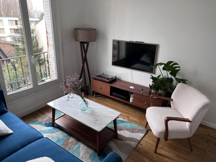 ein Wohnzimmer mit einem blauen Sofa und einem TV in der Unterkunft 20 min du Stade de France in Saint-Denis