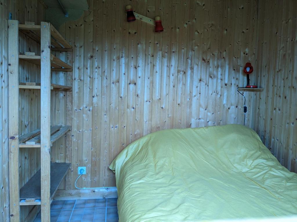 a bedroom with a wooden wall with a bed and a ladder at Au petit chalet d&#39;Illiers Combray in Illiers