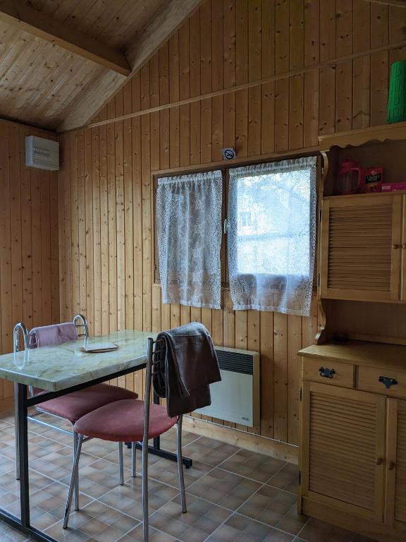 a kitchen with a table and two chairs and a window at Au petit chalet d&#39;Illiers Combray in Illiers