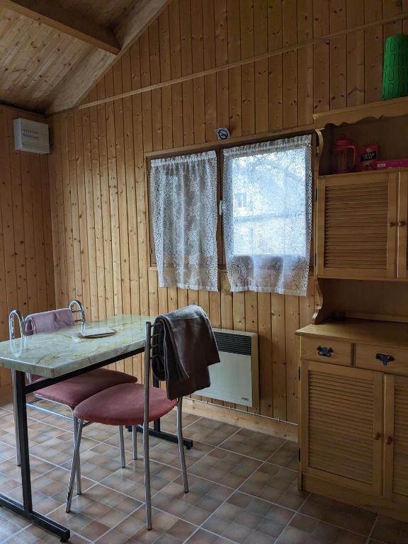 a kitchen with a table and two chairs and a window at Au petit chalet d&#39;Illiers Combray in Illiers