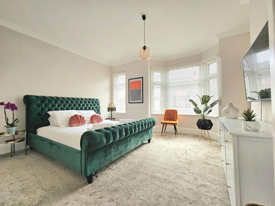 ein Schlafzimmer mit einem grünen Bett und einem Stuhl in der Unterkunft Contemporary Spacious 3BR House close to City Centre in Wyken