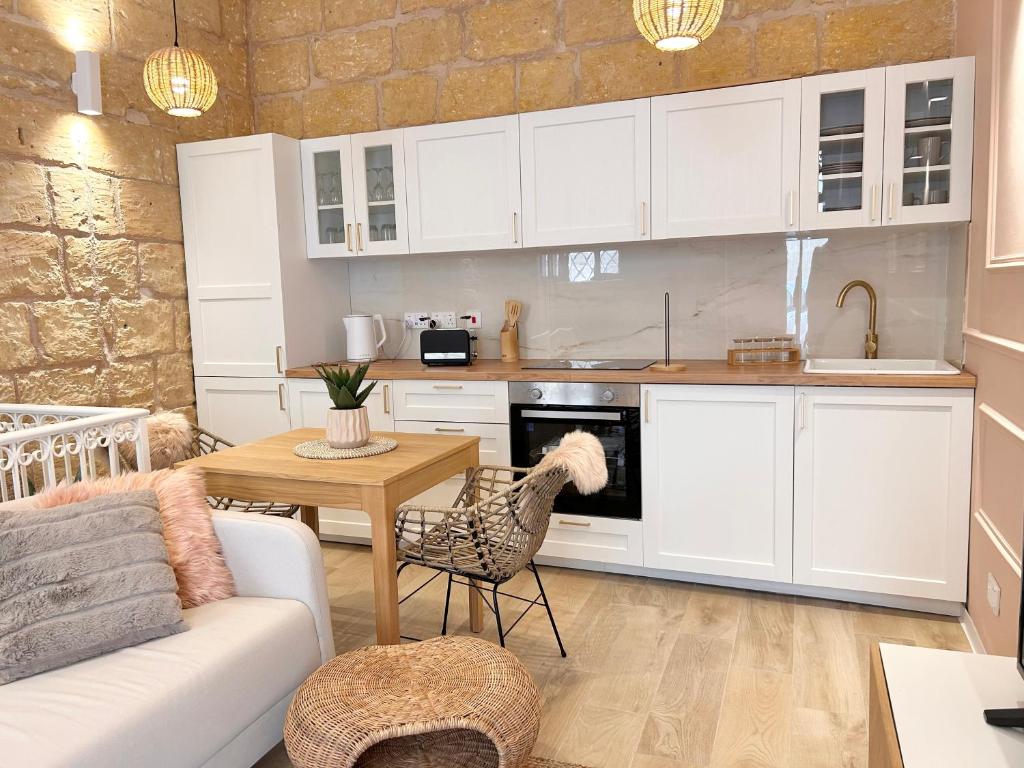 eine Küche mit weißen Schränken, einem Tisch und einer Couch in der Unterkunft MCC Argotti House in Floriana
