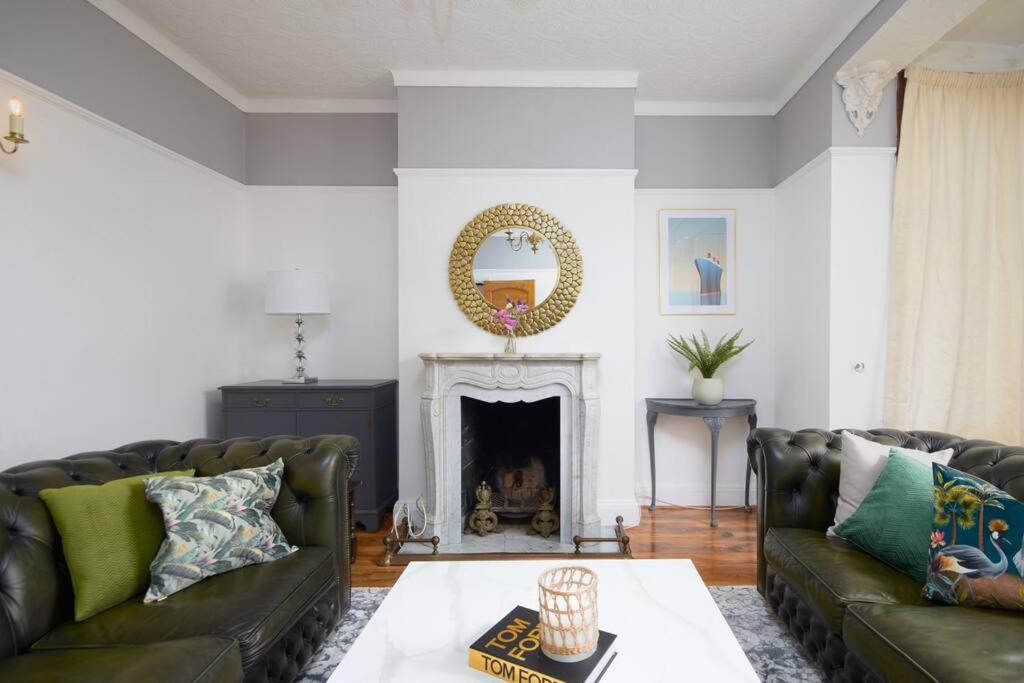 a living room with two leather couches and a fireplace at Large London home with Free parking in Winchmore Hill