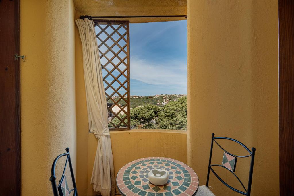mesa y sillas en una habitación con ventana en Casa Lilly by Wonderful Italy en Porto Cervo