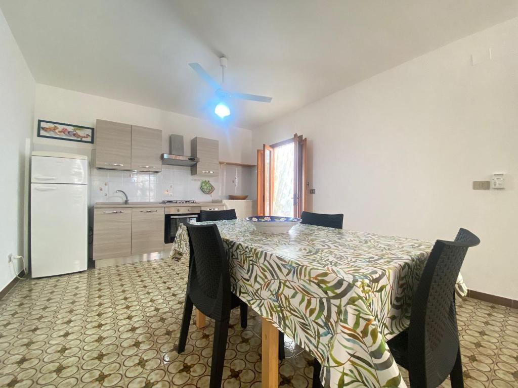 een keuken met een tafel met stoelen en een koelkast bij Marini Apartment by Diddoi in Marina di Mancaversa