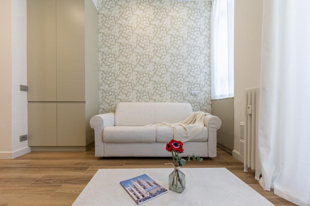 sala de estar con sofá y jarrón con flor en BePlace Apartments in De Angeli, en Milán