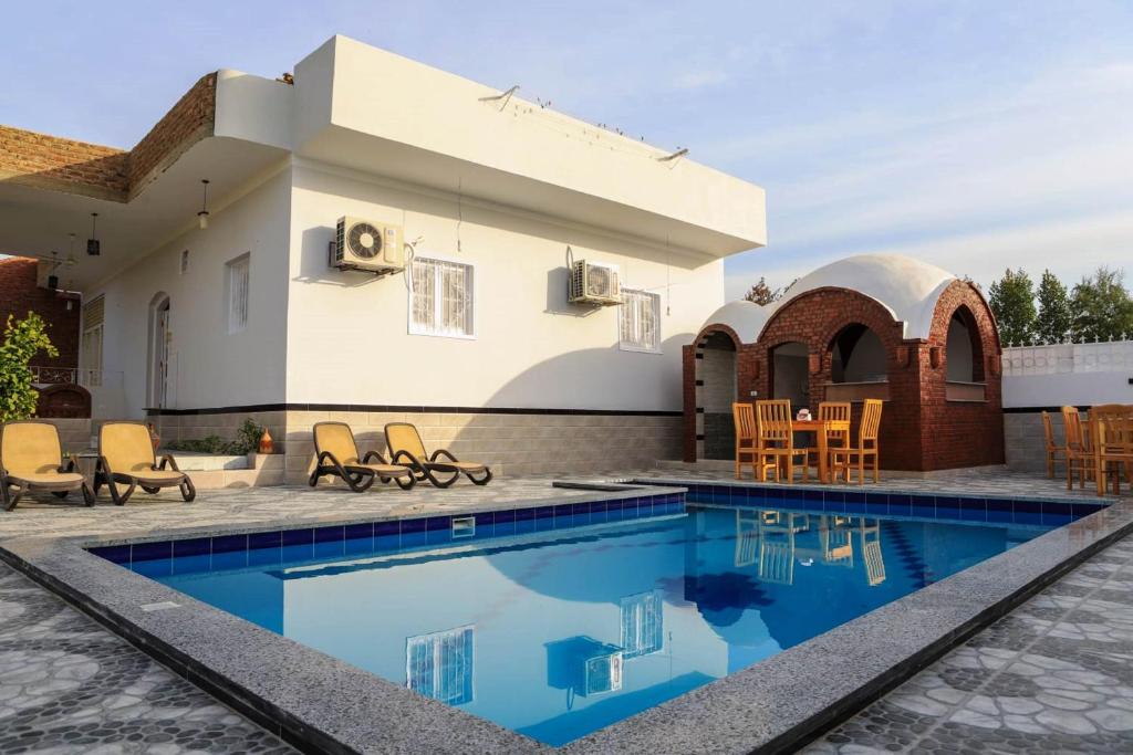 a villa with a swimming pool and a house at Happiness Guest House in Luxor