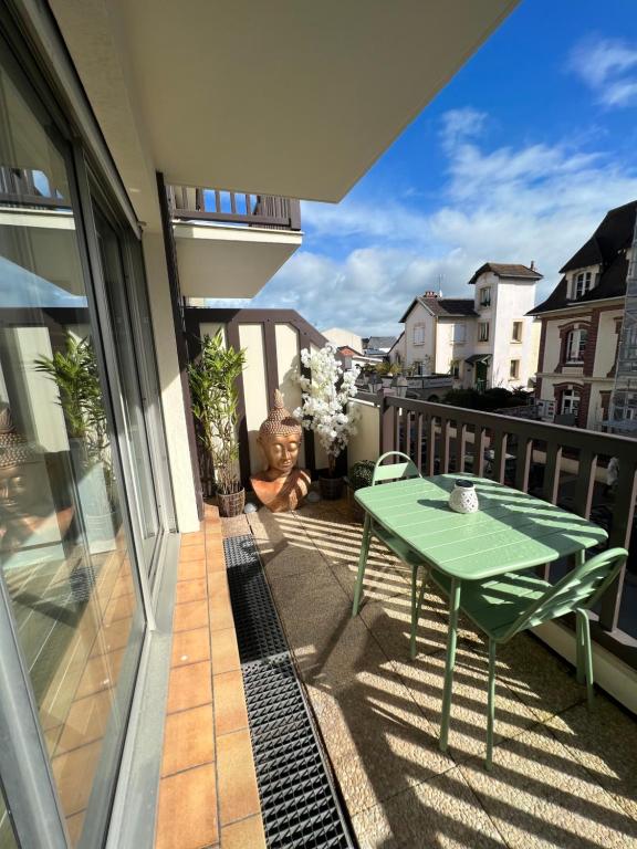 un tavolo verde sul balcone di una casa di Appartement hyper centre de Cabourg avec balcon a Cabourg