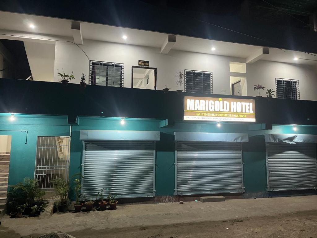 um edifício com três portas de garagem e um sinal nele em Marigold Hotel em Siliguri