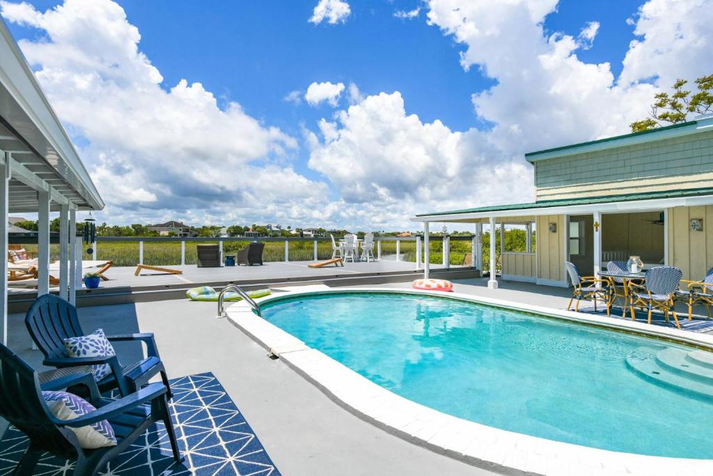 a swimming pool with chairs and a house at Sunset Dreams in Saint Augustine