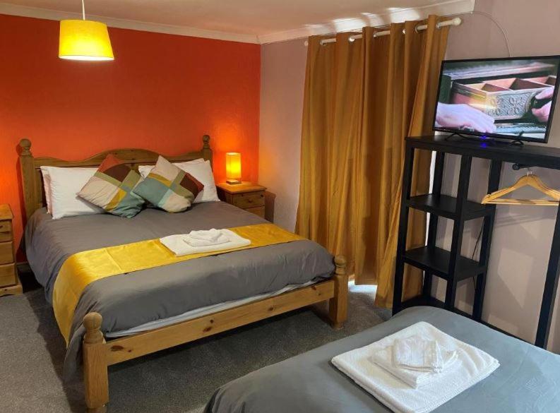 Kings Arms في Llandysul: غرفة نوم بسرير بحائط برتقالي