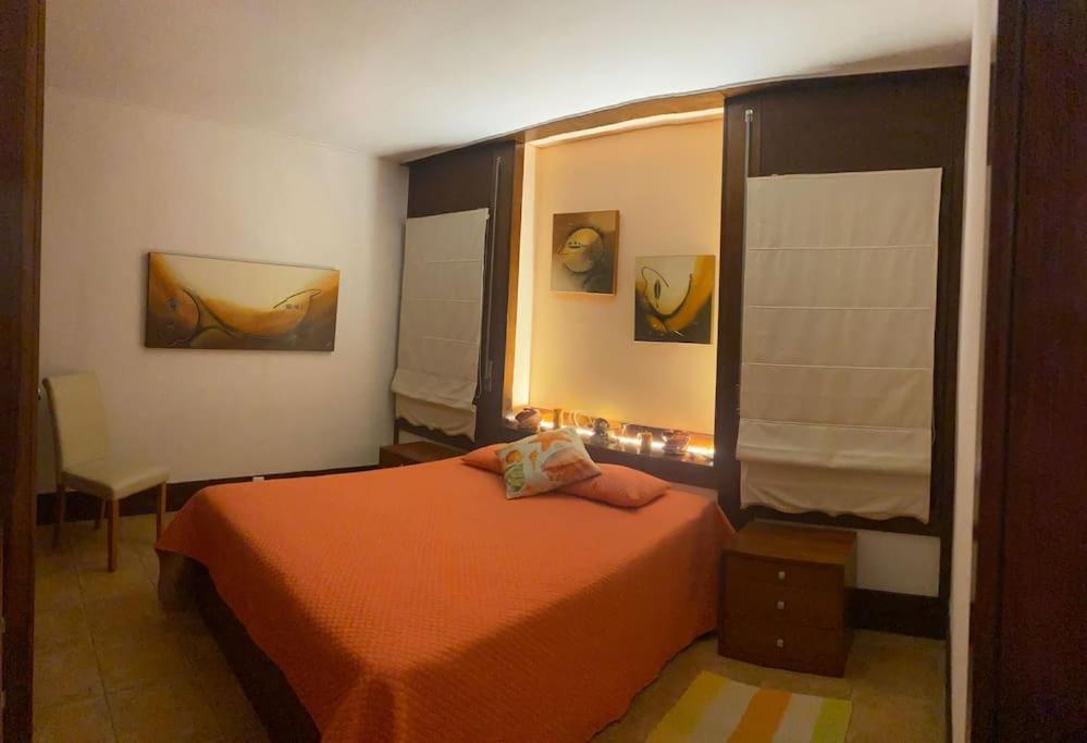 a bedroom with a orange bed and a window at Sunset Troia Beach in Troia