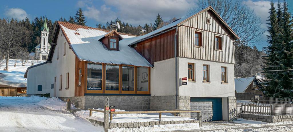 a large house in the snow with a snow covered yard at Apartmány Bedřichov pod kostelem in Bedřichov