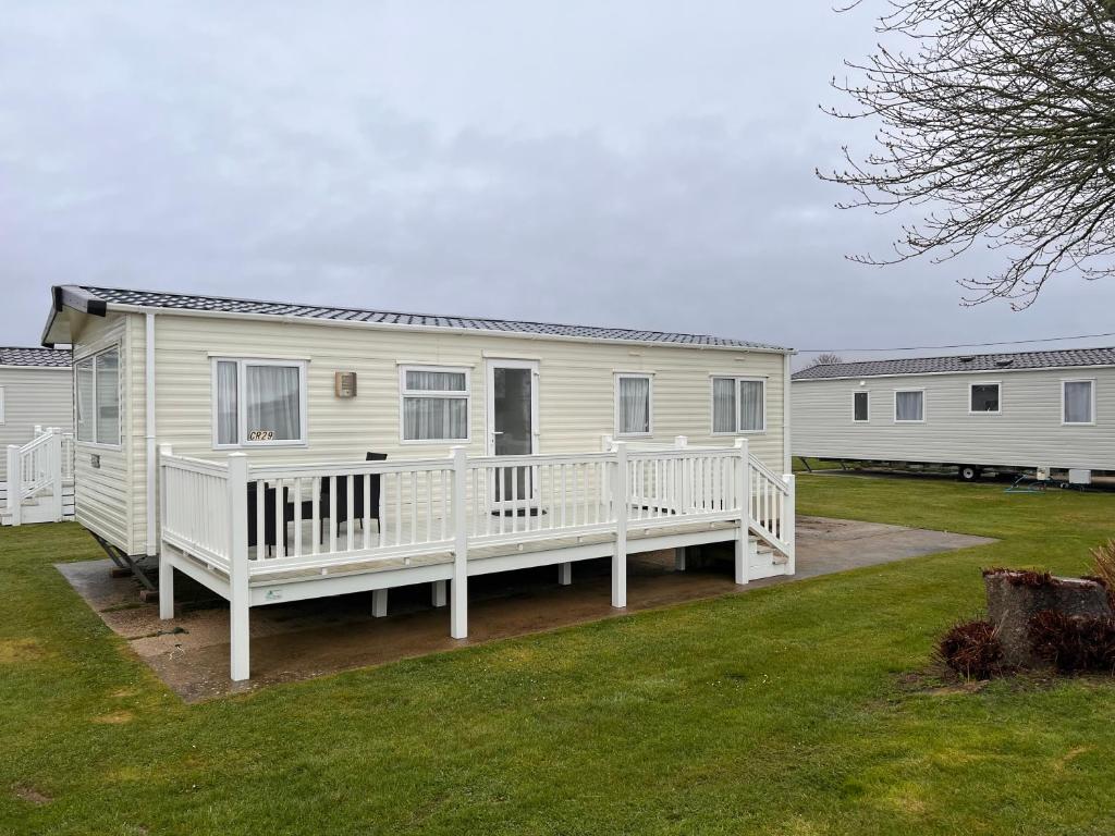 Casa móvil blanca con porche y patio en Home by the sea, Hoburne Naish Resort, sleeps 4, on site leisure complex available, en Milford on Sea