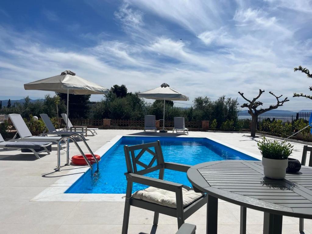 basen z krzesłami, stołem i parasolem w obiekcie Villa Evàlia - Private Villa With Pool -Malakonda ,Eretria ,Greece w Erétrii