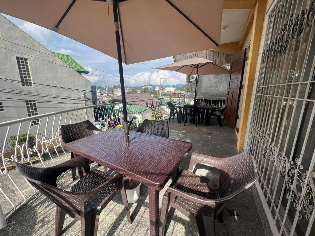 a table and chairs with an umbrella on a balcony at Baguio Camella Big Brother House in Baguio