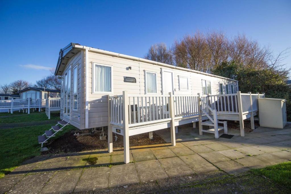 a white rv with a porch and a fence at Beautiful Lodge At Manor Park In Hunstanton Ref 23018k in Hunstanton