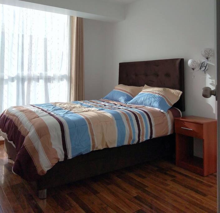 - une chambre avec un lit, une table de chevet et une fenêtre dans l'établissement Apartamento Cuzco, à Cusco