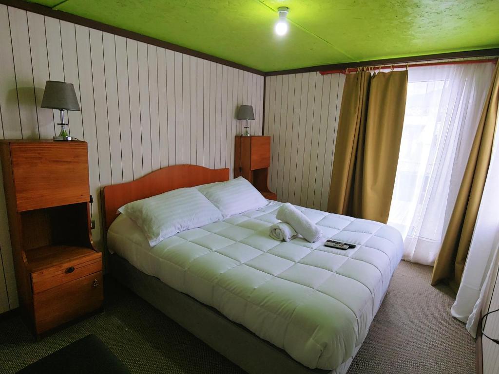 1 dormitorio con 1 cama grande con sábanas blancas en Catema, en Coyhaique