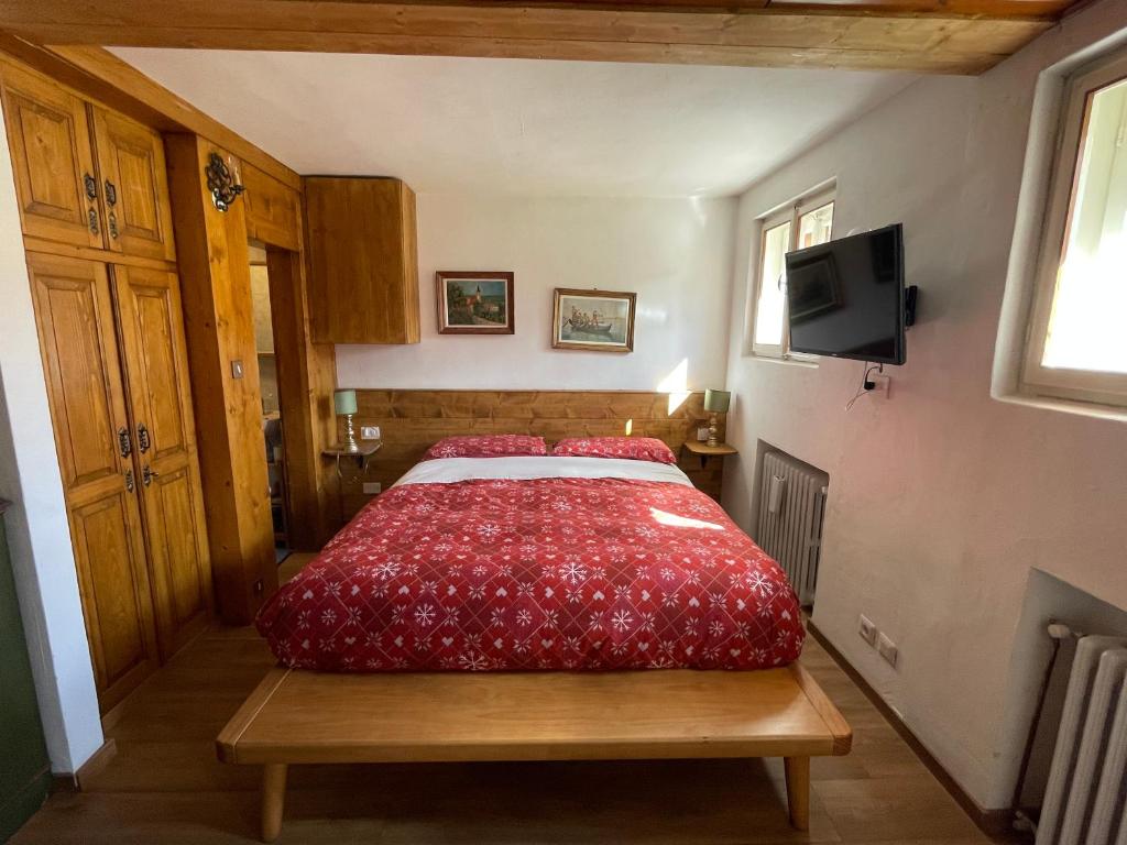 a bedroom with a bed with a red bedspread at La Roncolina in Cortina dʼAmpezzo