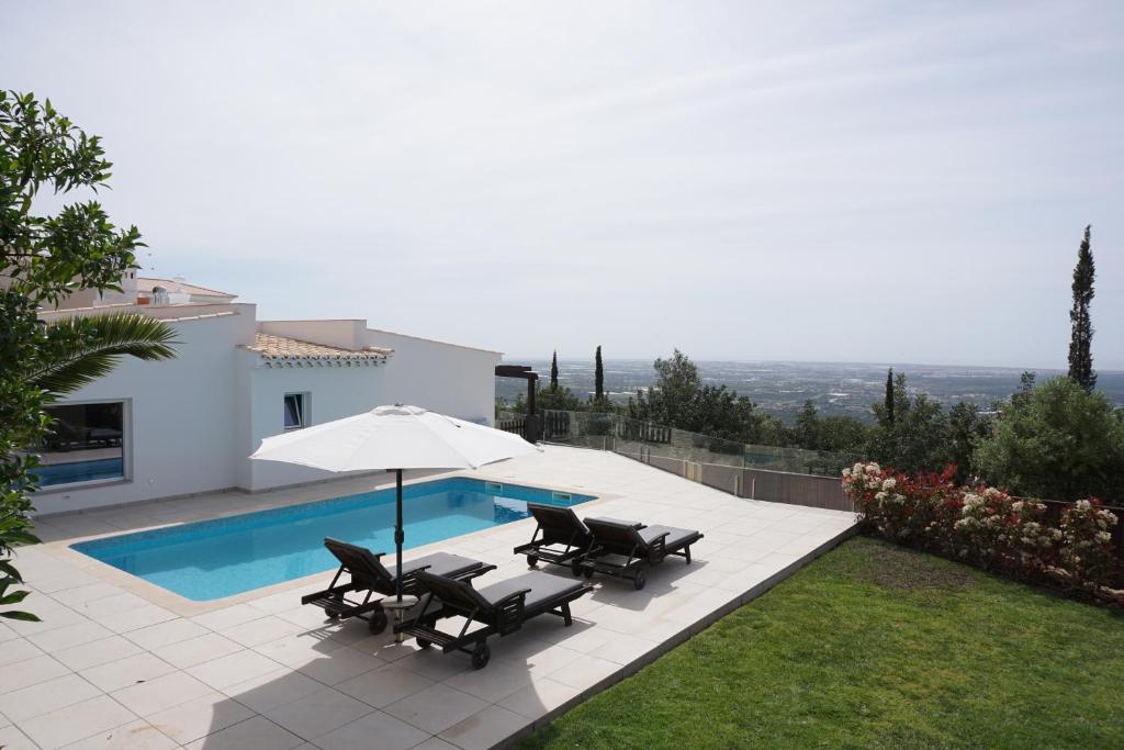 a patio with chairs and an umbrella next to a pool at Goldra Cozy Villa with private pool in Valados