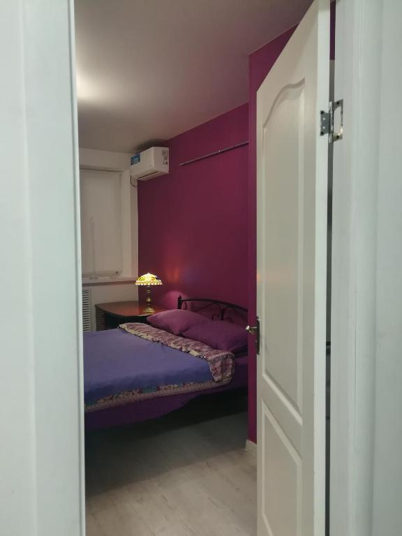 a bedroom with purple walls and a bed with a table at Квартира целиком Киев Подол метро Контрактовая площадь in Kyiv