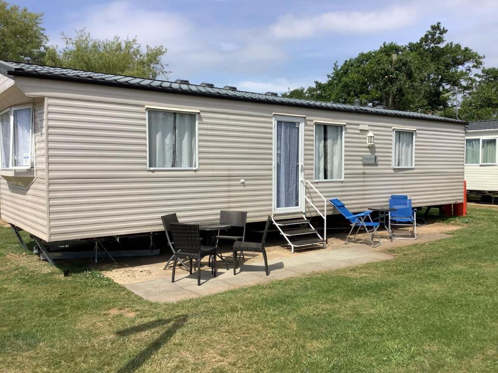 6 Berth Caravan For Hire In Hunstanton At Manor Park Holiday Park Ref 23004a في هونستنتون: كرفان فيه كراسي وطاولة أمامه