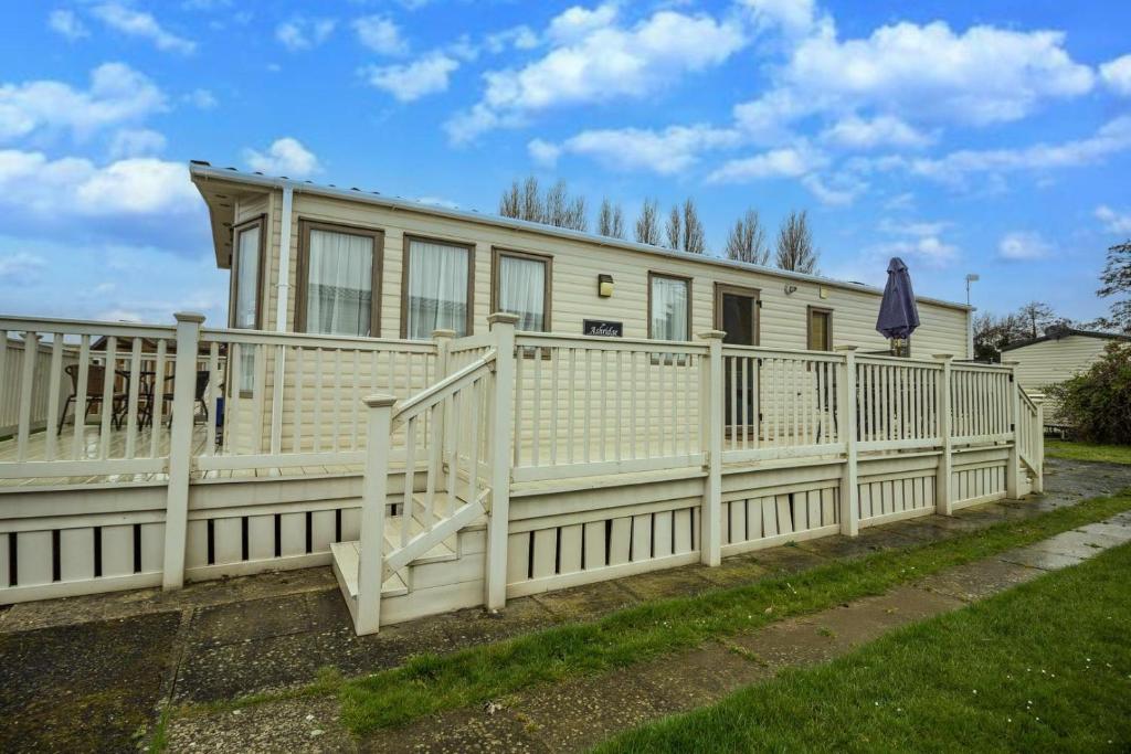 a house with a white fence in front of it at 6 Berth Caravan With Decking At Manor Park In Hunstanton Ref 23017h in Hunstanton