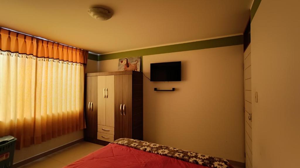 a bedroom with a bed and a cabinet and a television at Renacer apartamentos in Tacna