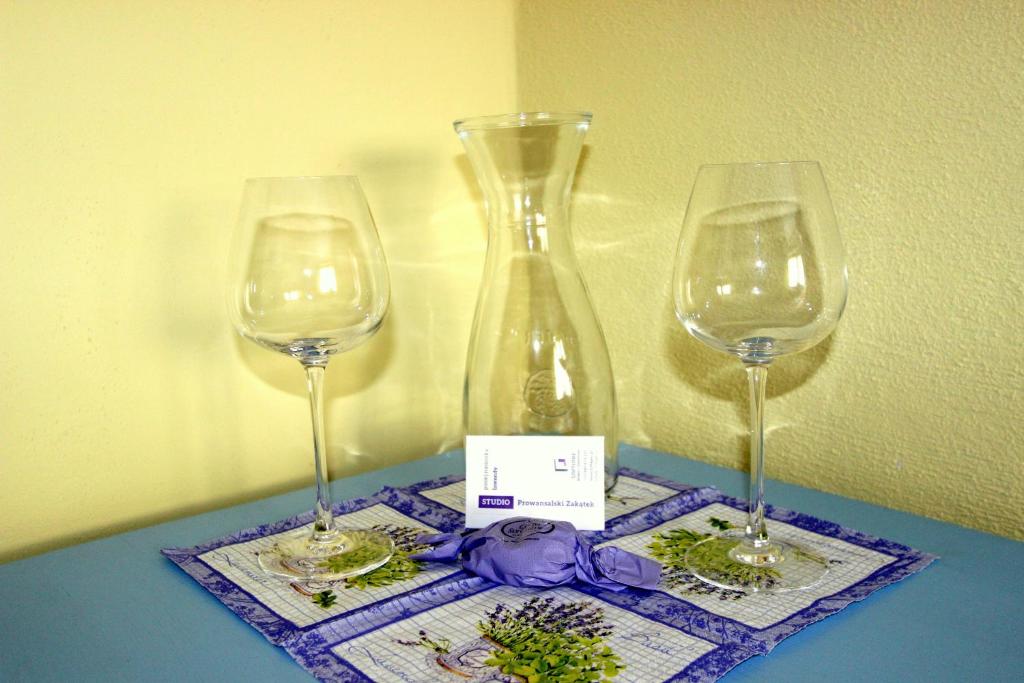 ウッチにあるDomek Podróżniczyのワイングラス2杯と花瓶1杯付きテーブル