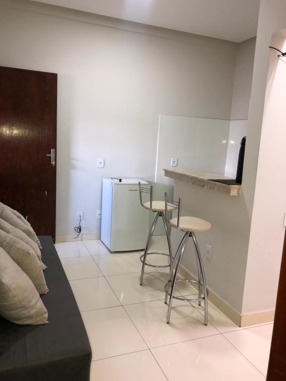 eine Küche mit einem Kühlschrank und 2 Hockern in einem Zimmer in der Unterkunft Flat Hotel in Guanambi