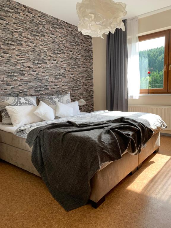 a bedroom with a large bed with a brick wall at Hof Görrespesch-Ferien im Herzen der Schneifel in Schlausenbach