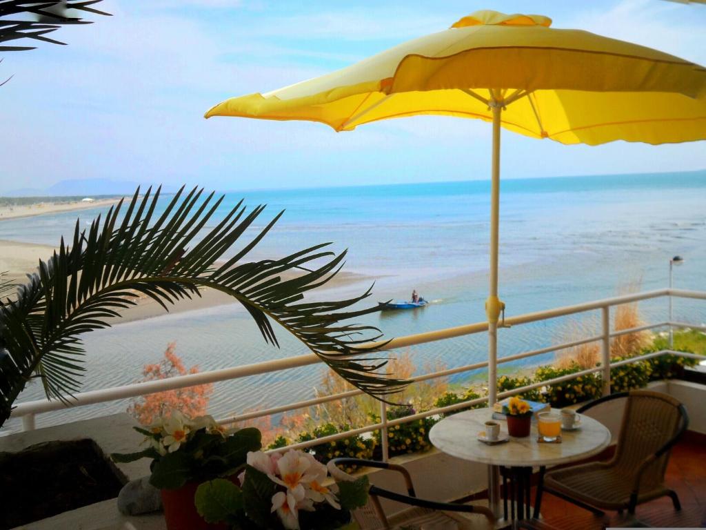 un balcón con una mesa y una sombrilla y la playa en Apartments Kepi Gjerana, en Ulcinj