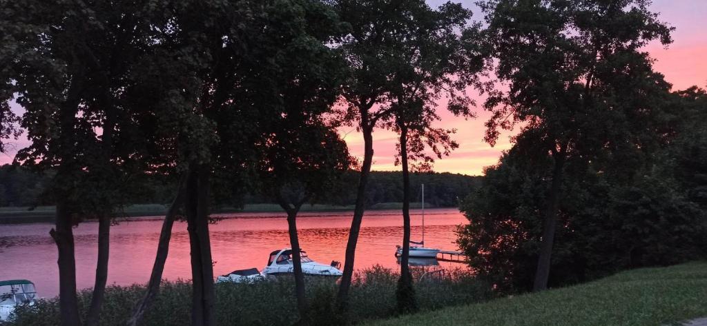 a boat is docked on a river at sunset at u Tymka in Iława