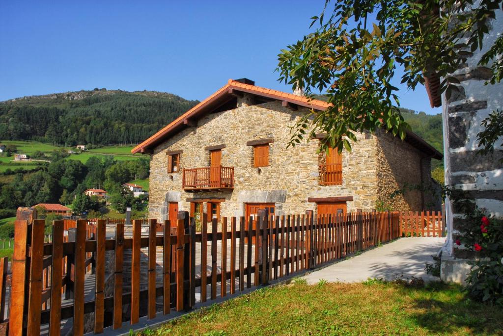 una casa de piedra con una valla de madera delante de ella en Caserio Gaztelu en Gaztelu