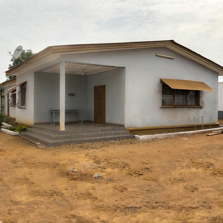 ein kleines weißes Gebäude mit einer Veranda und einer Tür in der Unterkunft Chez Catherine et Gabriel in Bangui