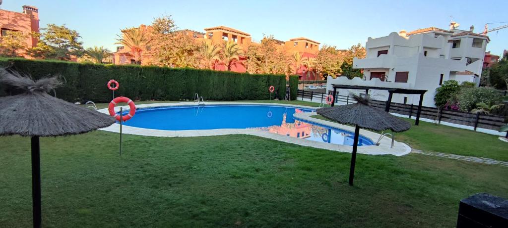 uma piscina com dois guarda-sóis num quintal em Appart cosy Golf Garden Casares em Casares