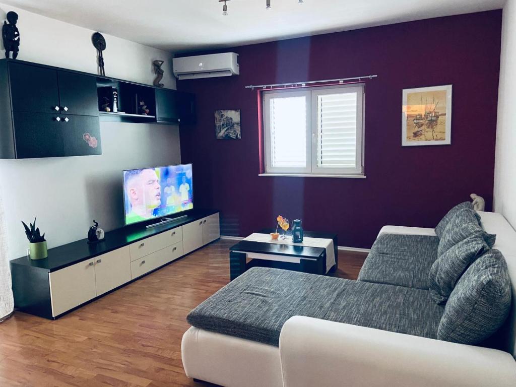 a living room with a couch and a flat screen tv at Apartments Gule in Slatine