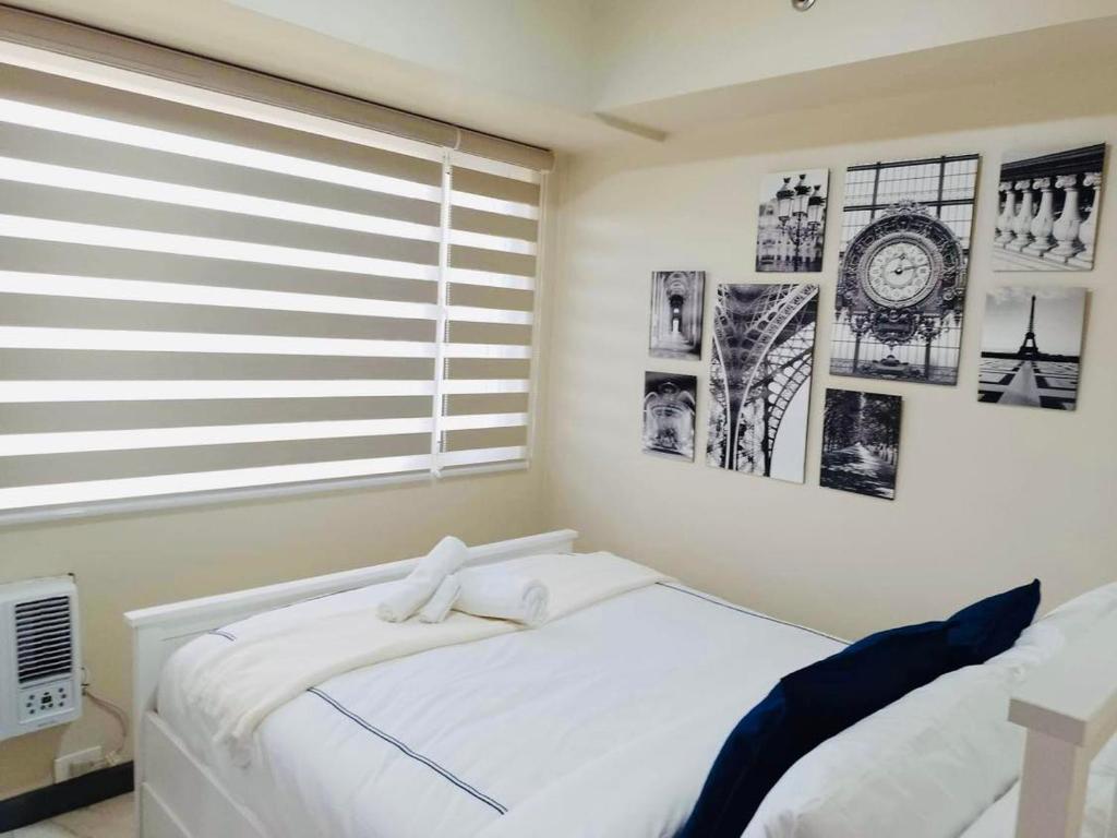 een slaapkamer met een wit bed en een raam bij Larue cozy room in Solemare Parksuites Paranaque in Manilla