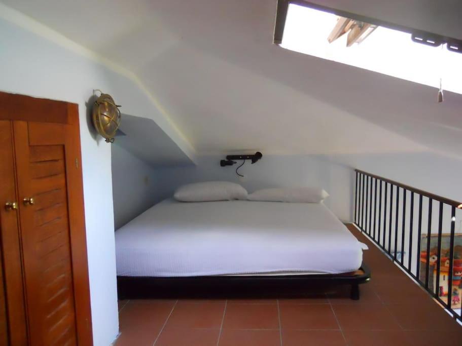 een slaapkamer met een wit bed op zolder bij Appartamento con piscina e aria condizionata in La Maddalena