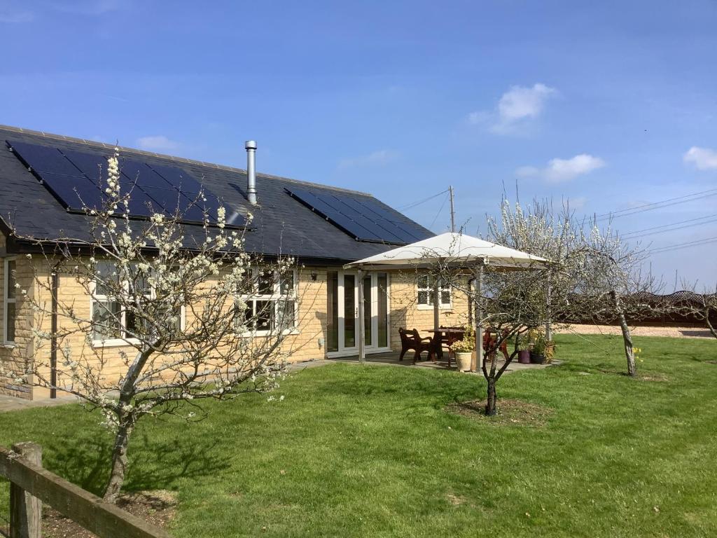 a house with a solar roof and a yard at Orchard Cottage, Clematis cottages, Stamford. Accessible luxury home. in Stamford