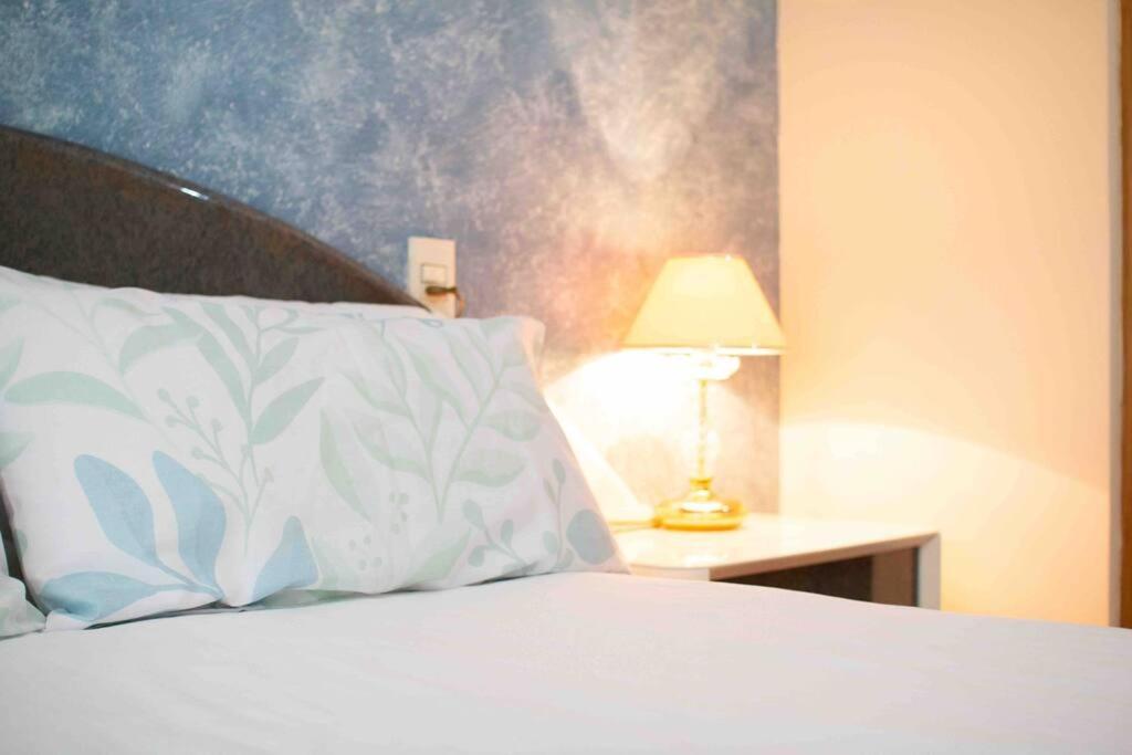 un letto con un cuscino bianco e una lampada sul tavolo di Gran apartamento con parking a 10min de la playa a Castellón de la Plana