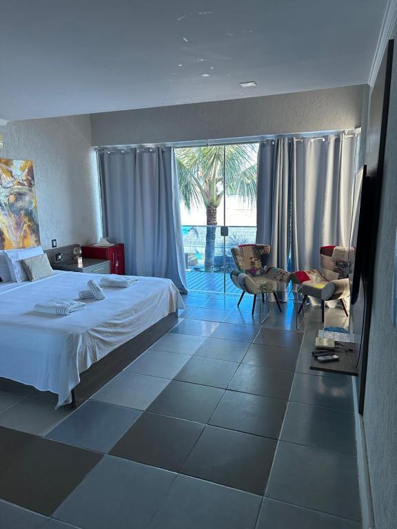 Cette chambre comprend un lit et une grande fenêtre. dans l'établissement Residência Angra Deep Blue, à Angra dos Reis