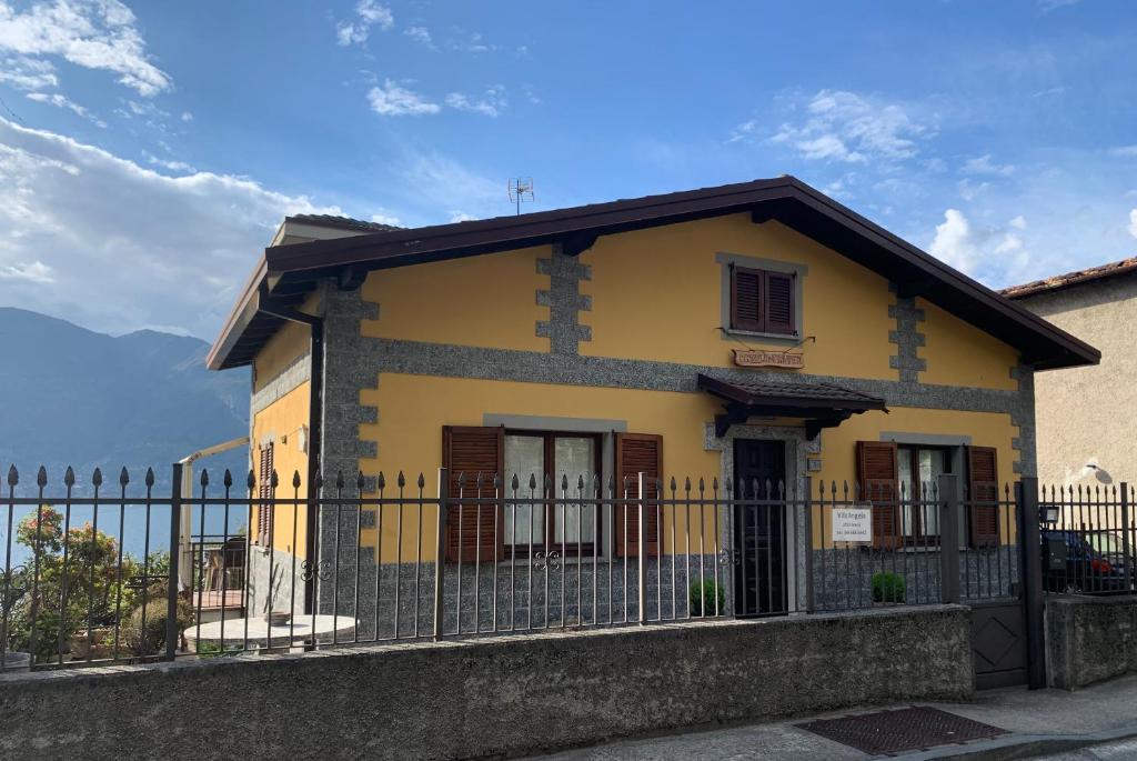 a yellow house with a fence in front of it at Villa Angela in Dorio