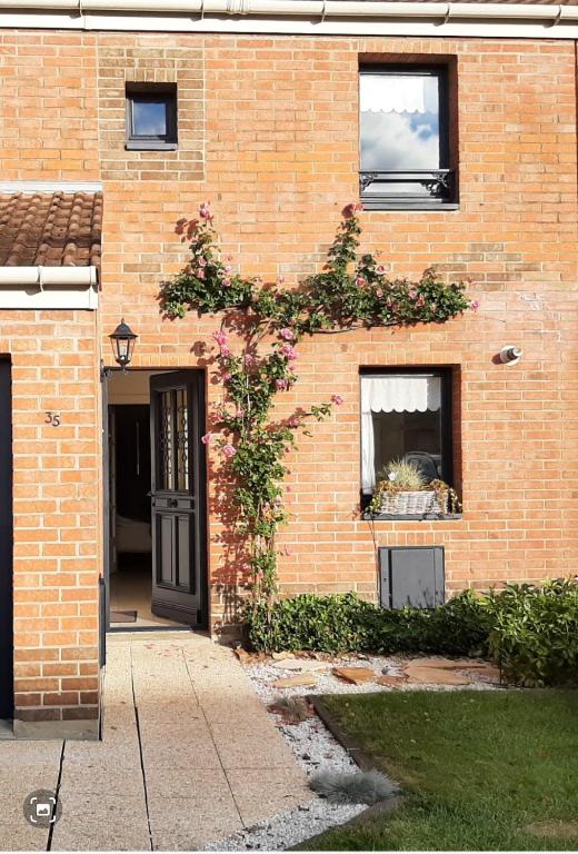 un bâtiment en briques avec une porte et une plante dans l'établissement CHEZ FLO, à Saint-Léonard
