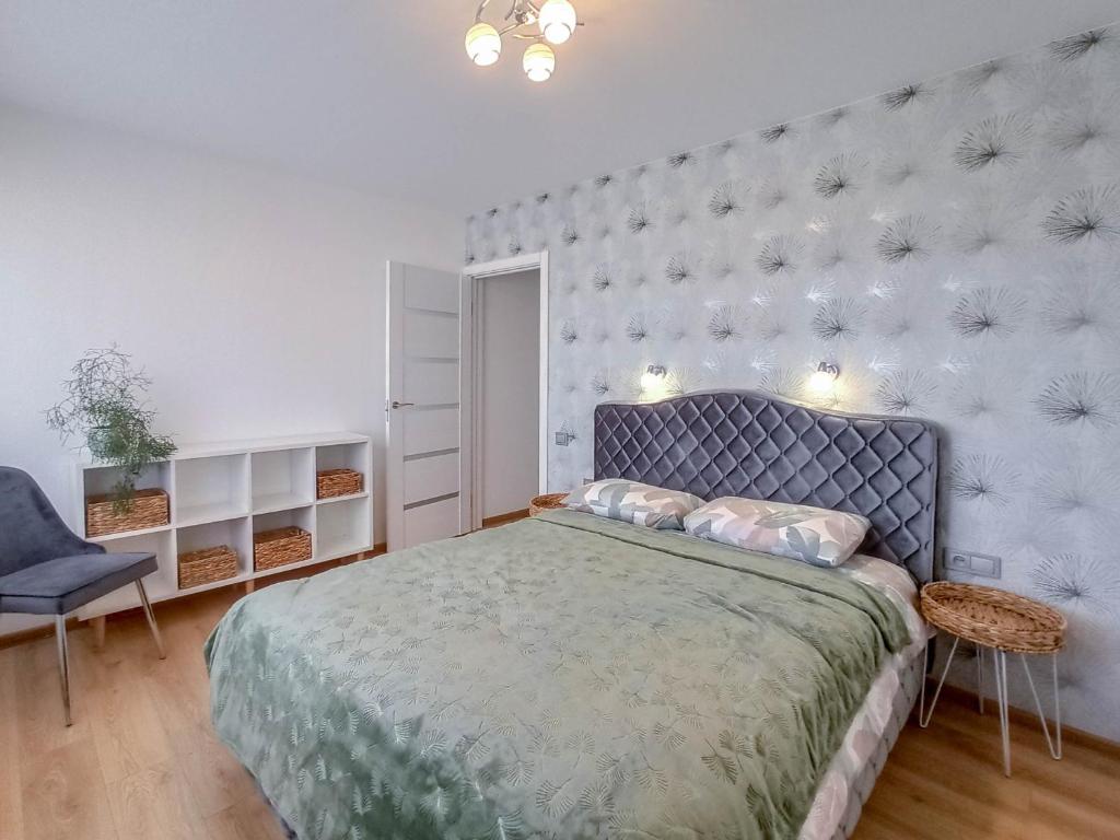 a bedroom with a large bed with a blue headboard at Apartamentai ramioje vietoje in Šiauliai