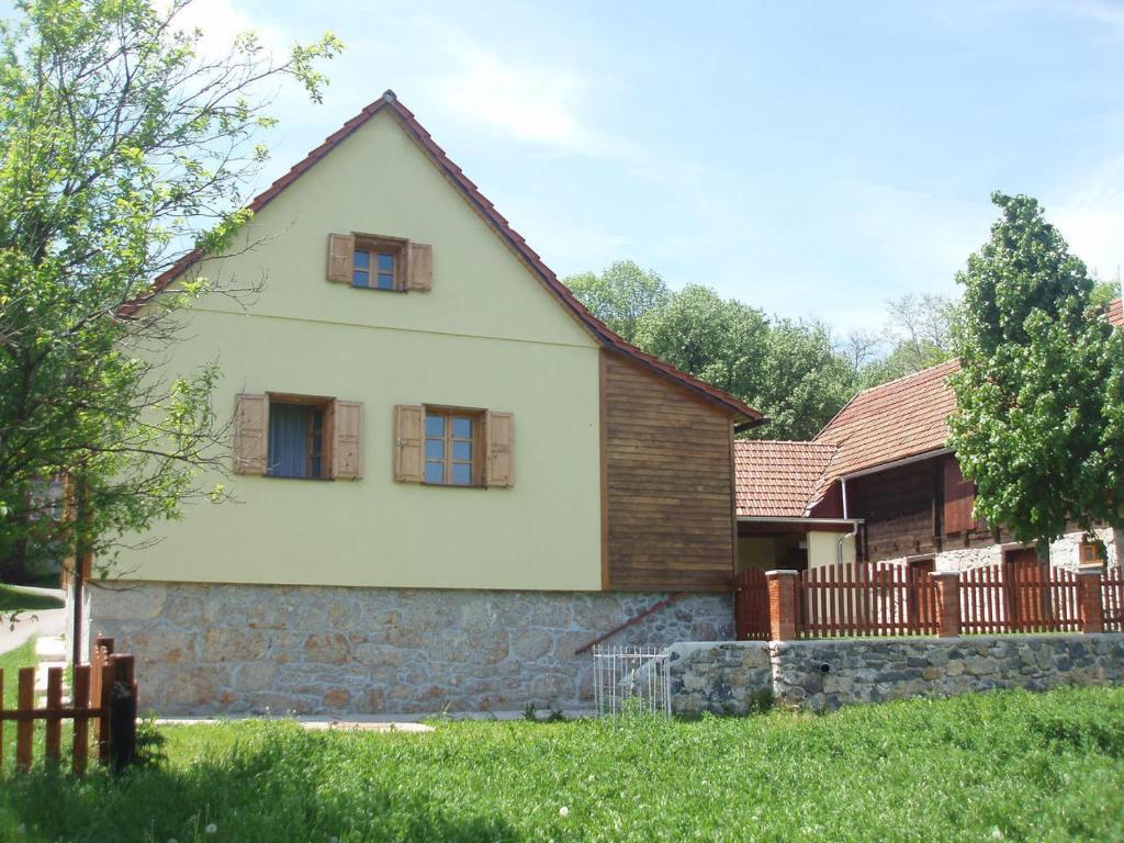 ein Haus mit einer Steinmauer und einem Zaun in der Unterkunft Kuća za odmor Vučetić in Brinje