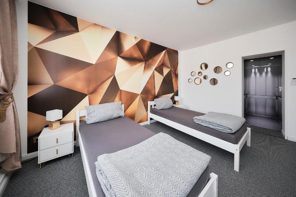 a bedroom with two beds and a geometric wall at Anhalt Pension in Coswig